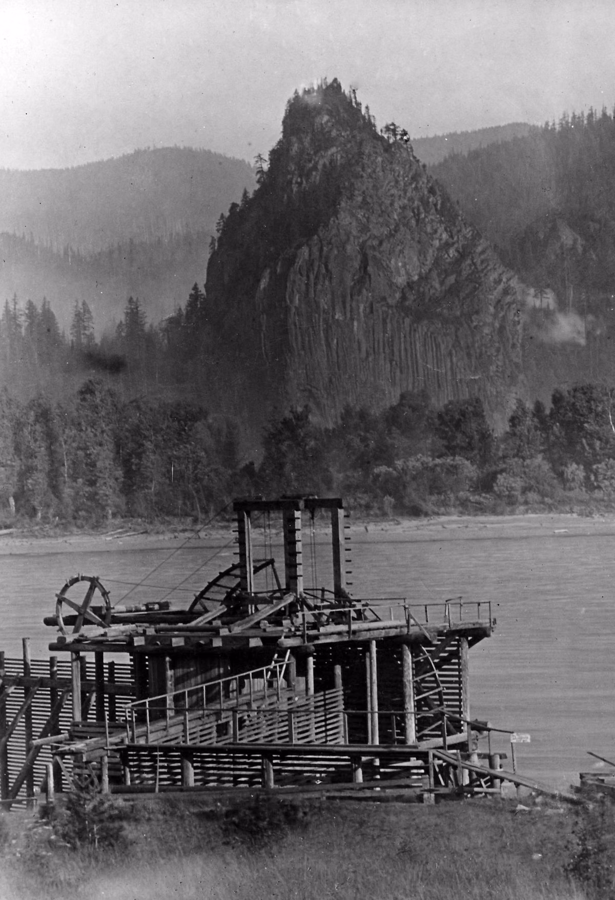 Historic photo of a fish wheel on the Columbia River with Beacon Rock behind it
